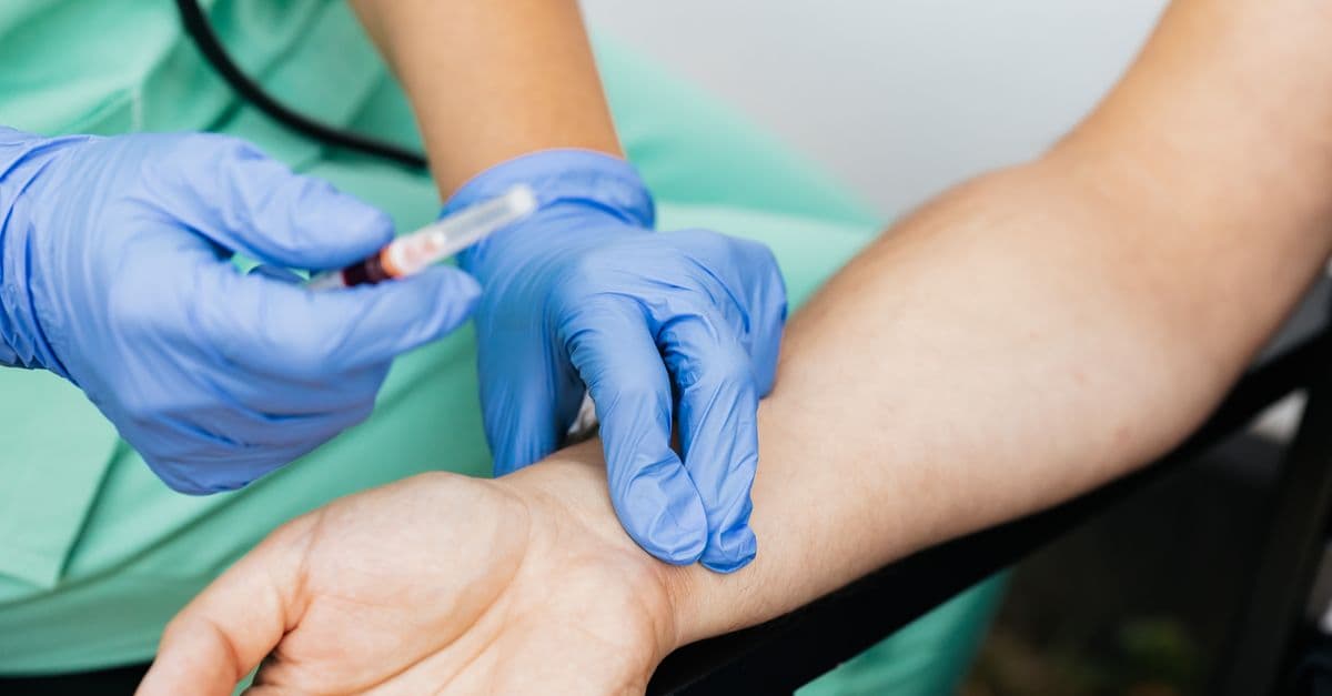 Close-up of nurse checking pulse and preparing syringe for medical use.