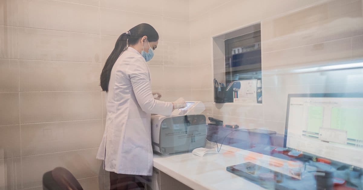 Woman in a lab coat examines equipment in a laboratory environment, Baku, Azerbaijan.