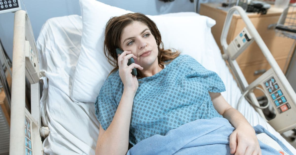 Woman in hospital bed talking on phone, representing healthcare and patient communication.