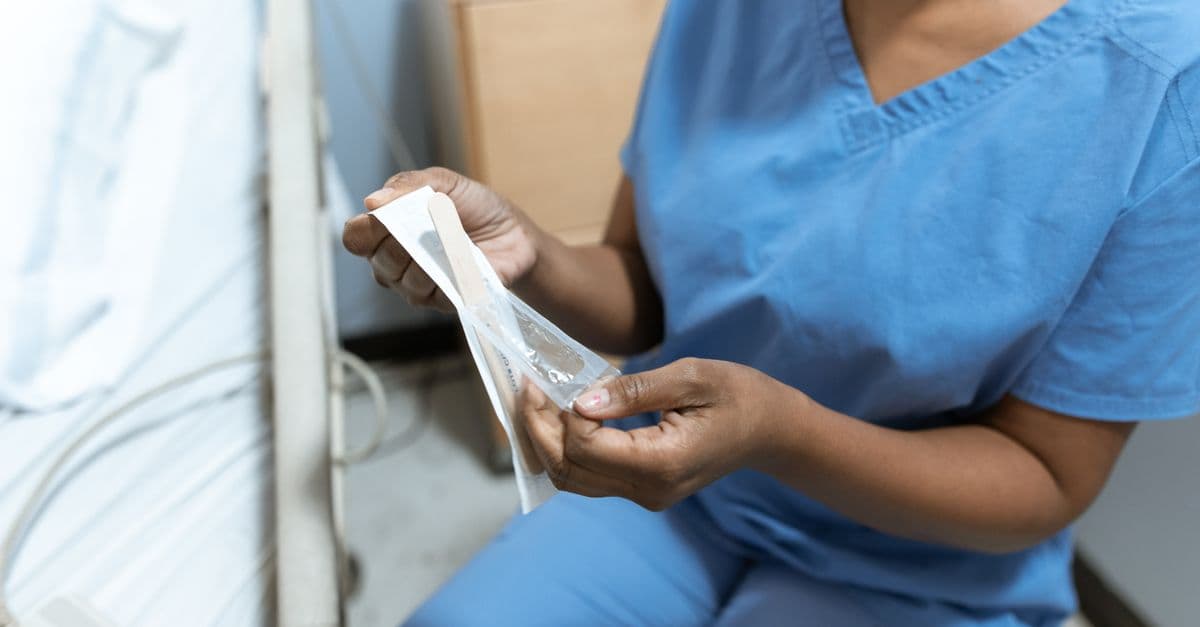 Close-up of a nurse unwrapping medical tools in a hospital setting, emphasizing care.
