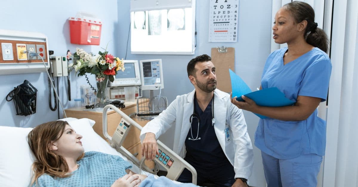 Doctors and nurse discussing patient's treatment in a hospital room.