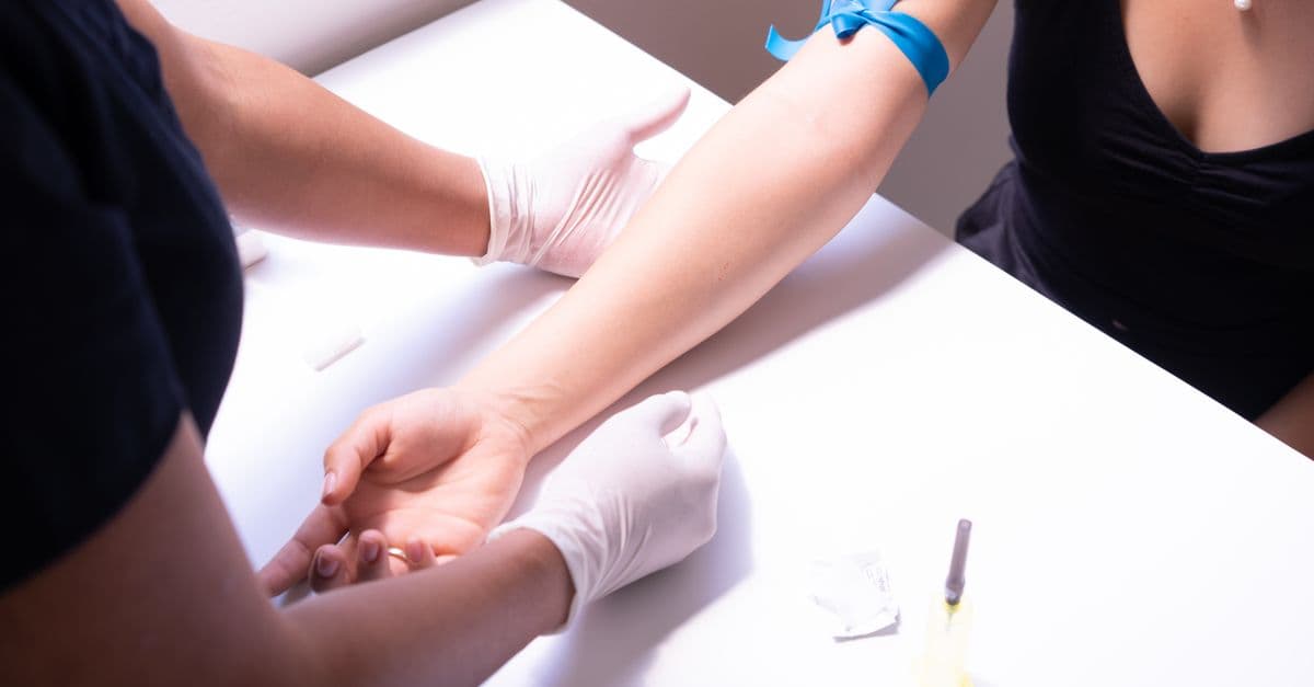 Healthcare professional performing blood sampling for medical testing with a focus on disease prevention.