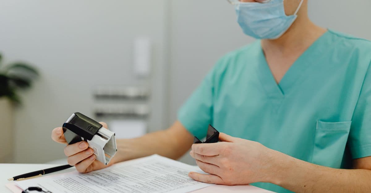 Healthcare worker in scrubs reviewing patient files with a stamp and clipboard.