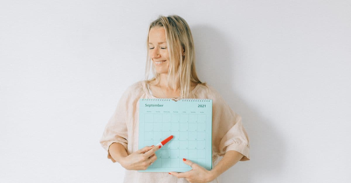 Smiling woman points at a date on a calendar, conveying excitement and anticipation.