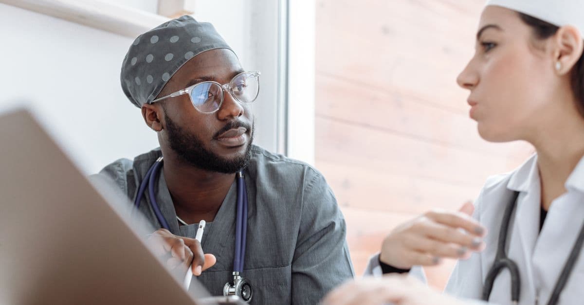 Two healthcare workers in conversation, focusing on collaboration and patient care.